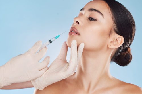 Beautiful young mixed race woman getting plastic surgery botox injection into her lips. Attractive .